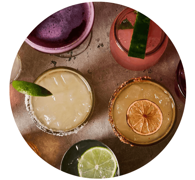 A round table with drinks and a lime wedge.