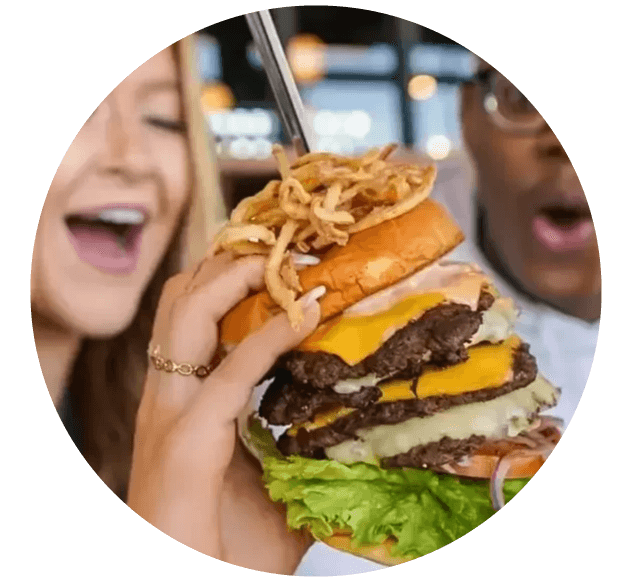 A close-up photo of a juicy burger with a toasted bun, lettuce, tomato, cheese, and a beef patty, held together.